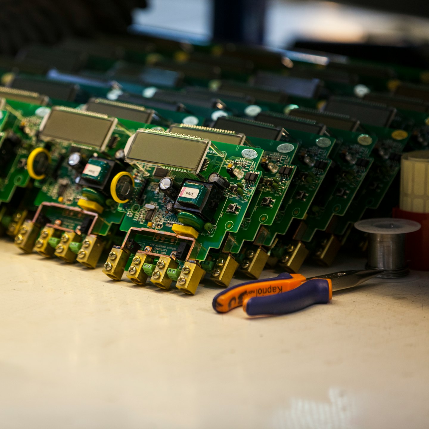 Stacked green circuit boards with electronic components and brass connectors.