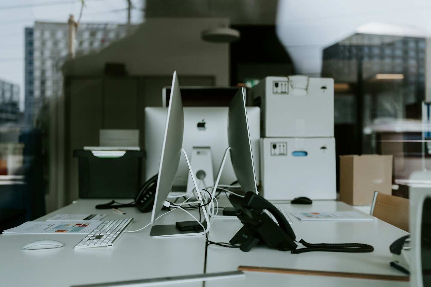 Modern office desks with computers and phones in a workspace.