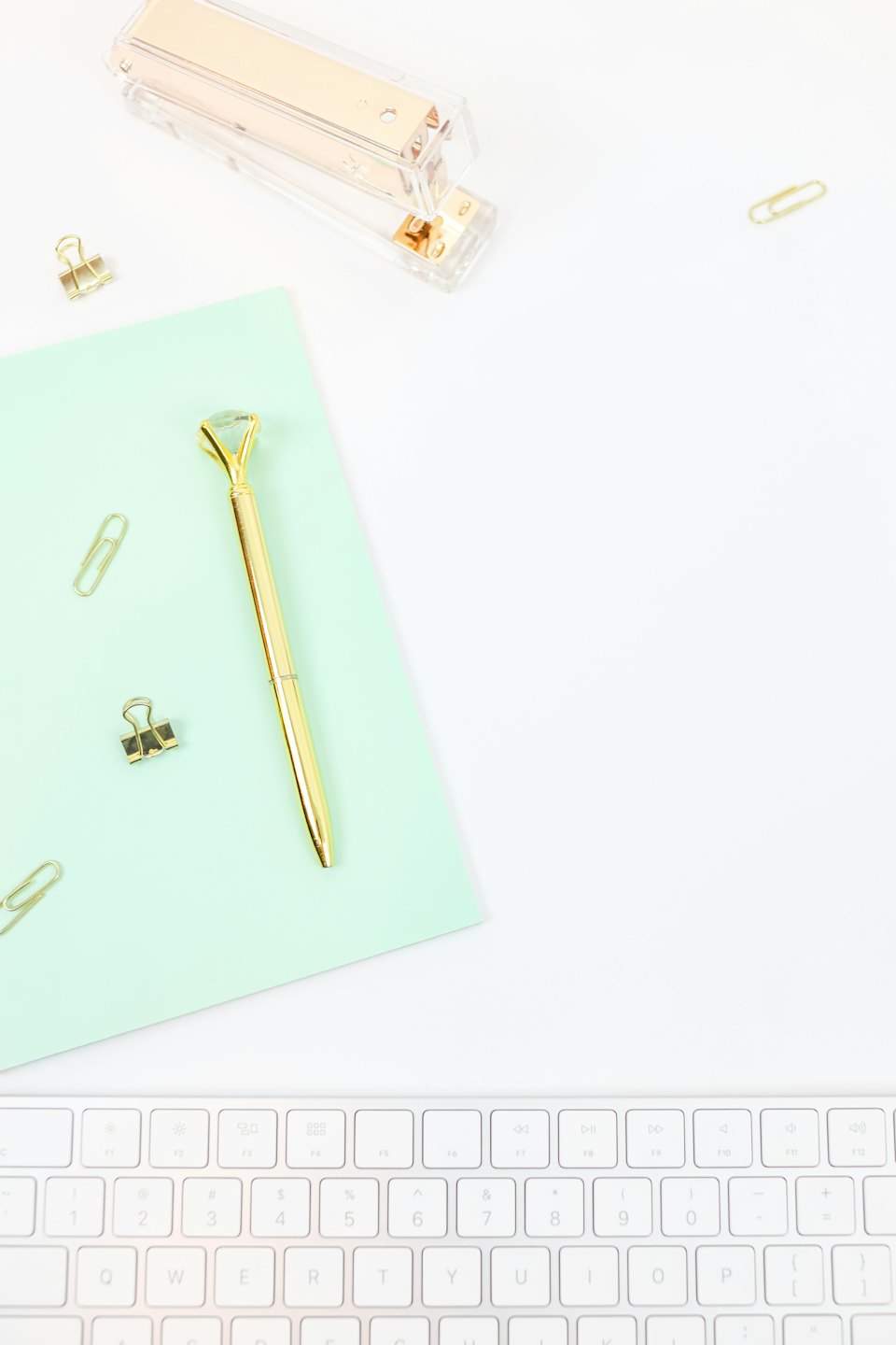 Modern office supplies including a stapler, pen, and paper clips on a white desk.